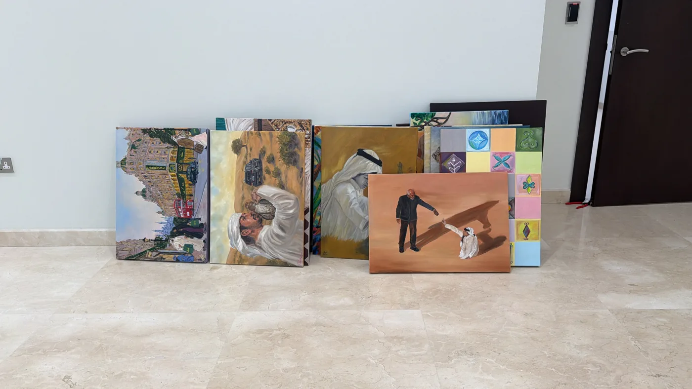Canvases from Traces of Home leaned against a wall, some on their sides, including the Harrods street scene and the falconer